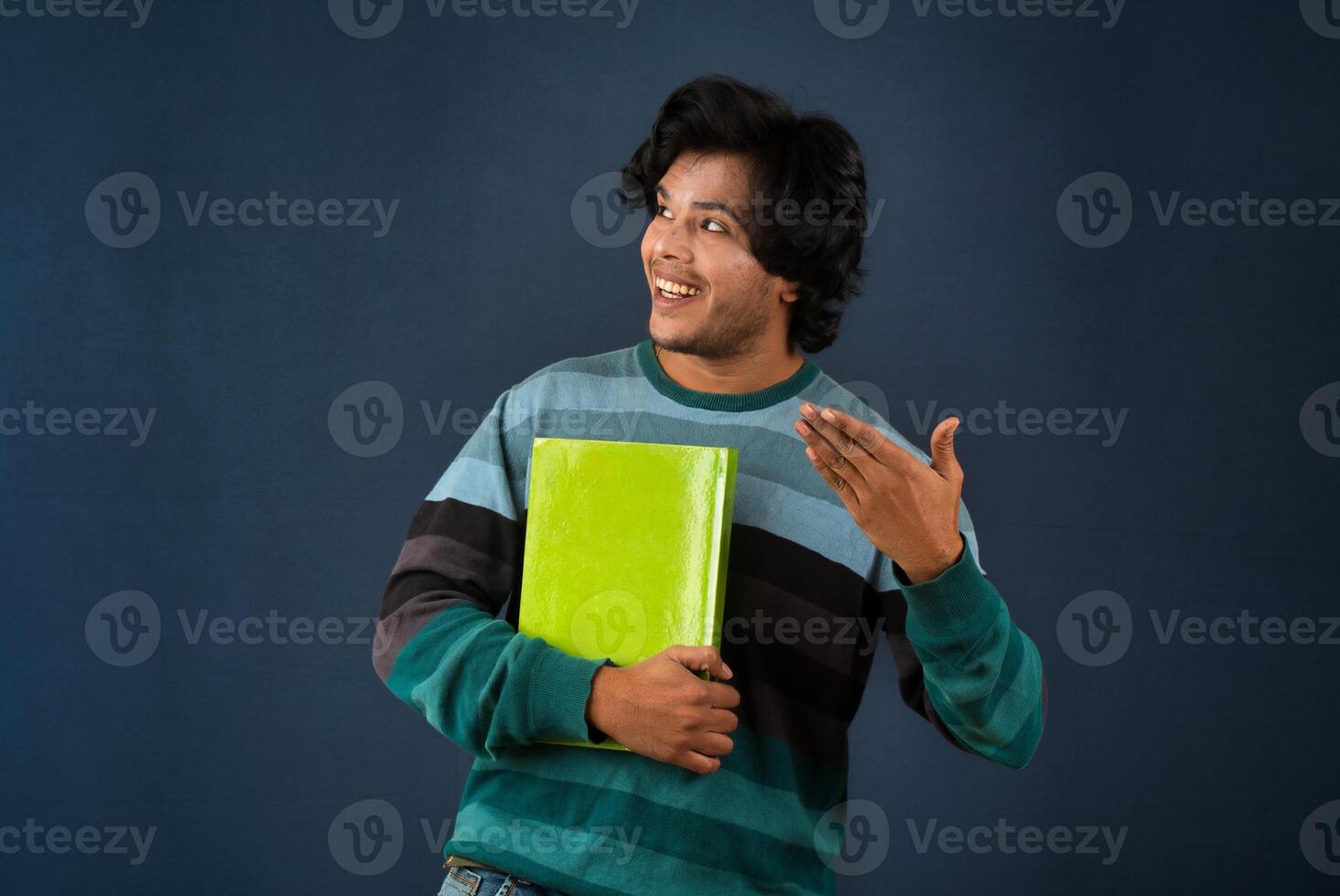 Young happy man holding and posing with the book on background. photo