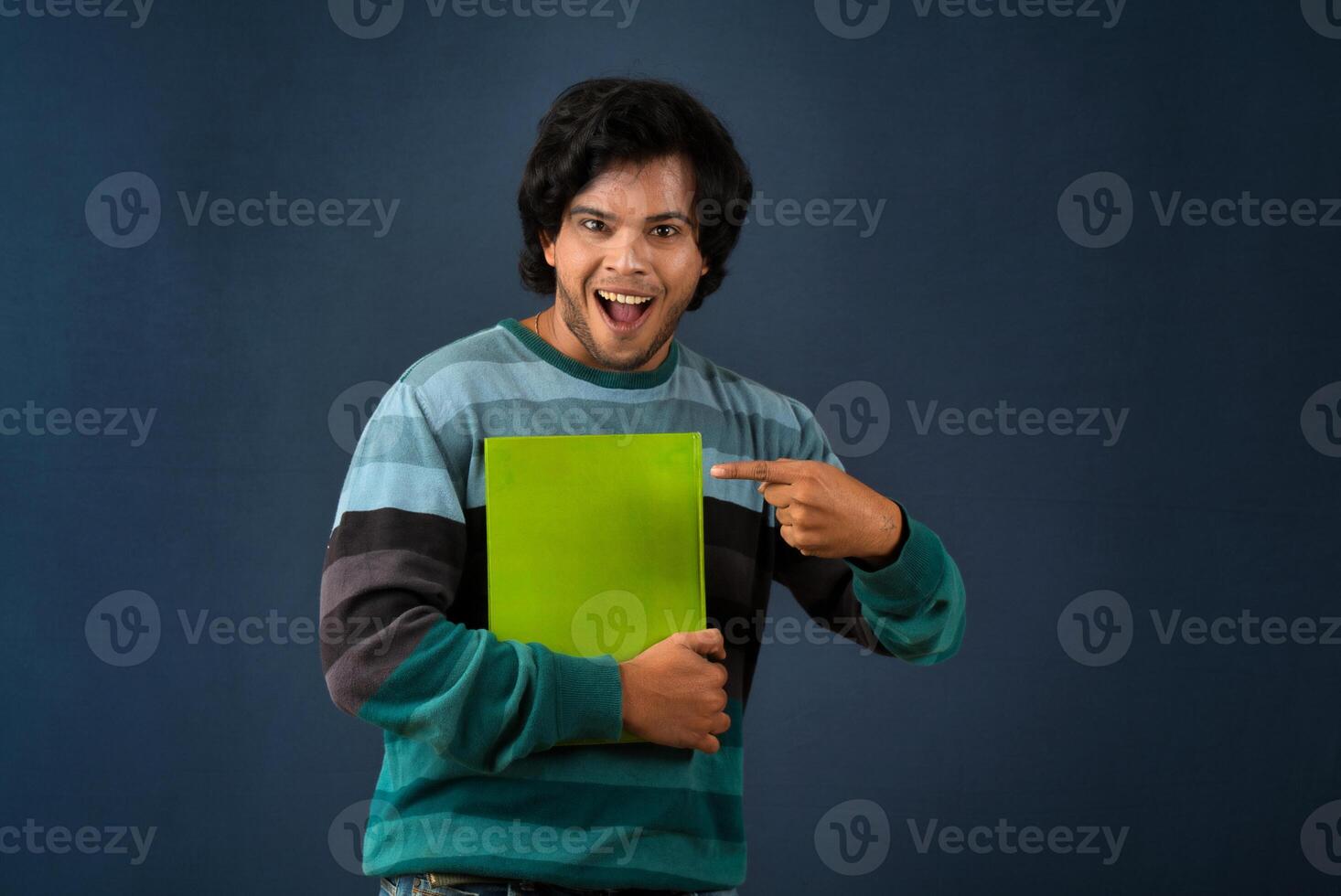 Young happy man holding and posing with the book on background. photo
