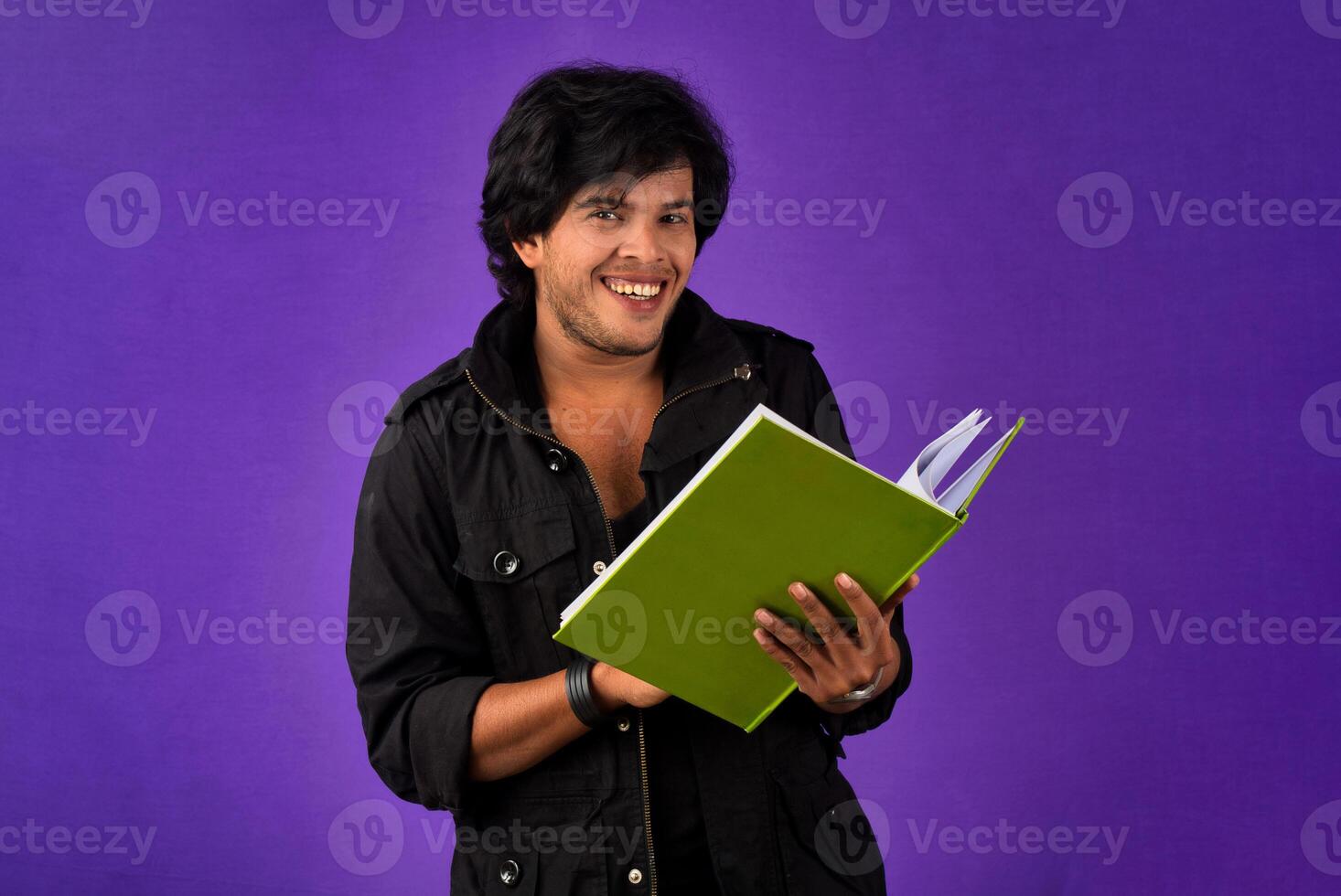 Young happy man holding and posing with the book on background. photo