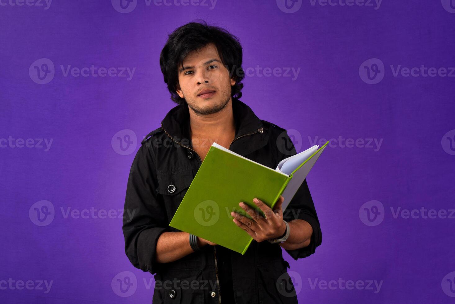 Young happy man holding and posing with the book on background. photo