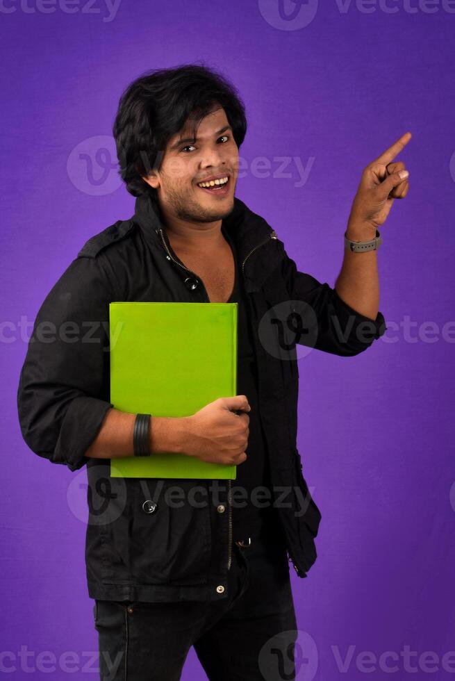 Young happy man holding and posing with the book on background. photo