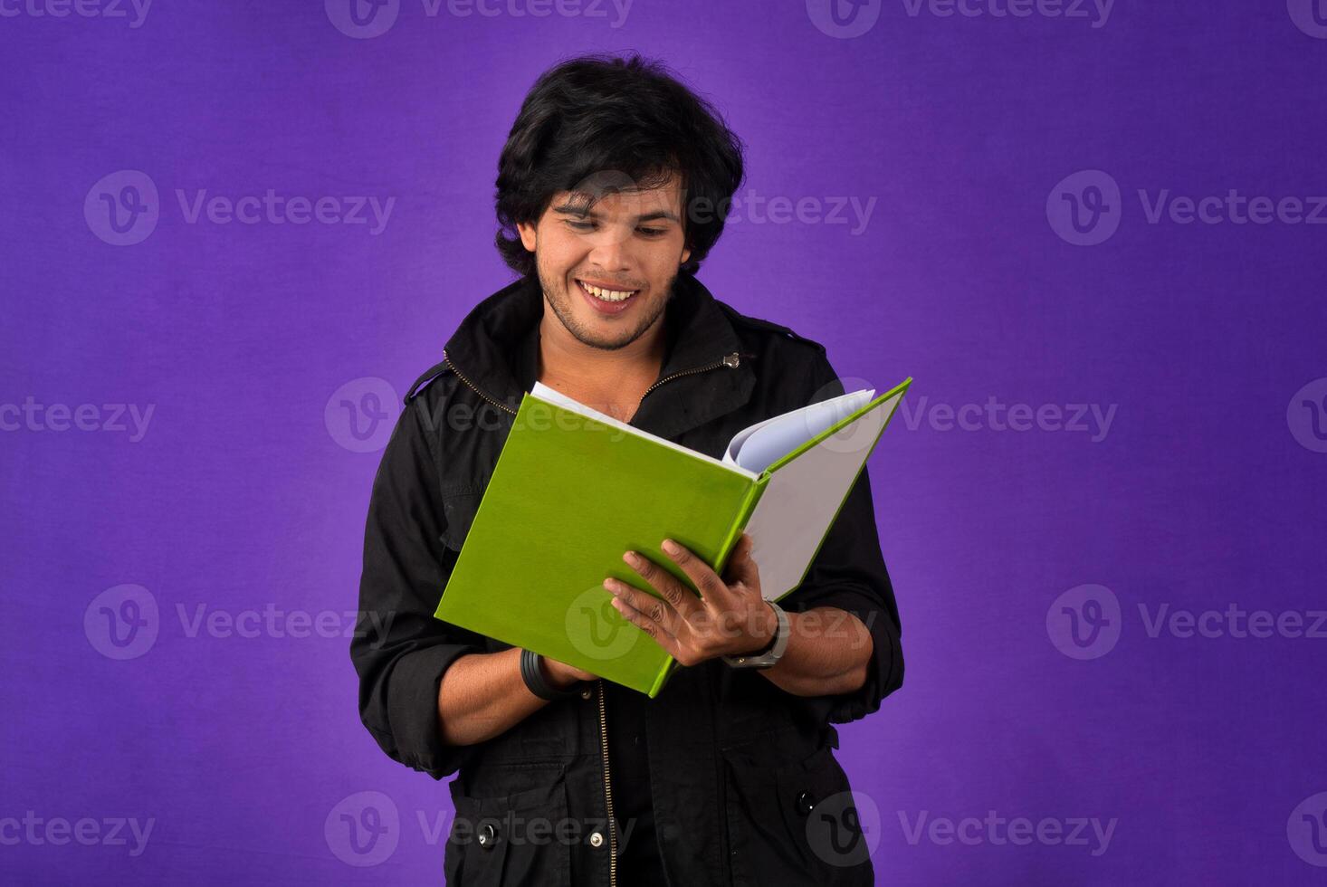 Young happy man holding and posing with the book on background. photo