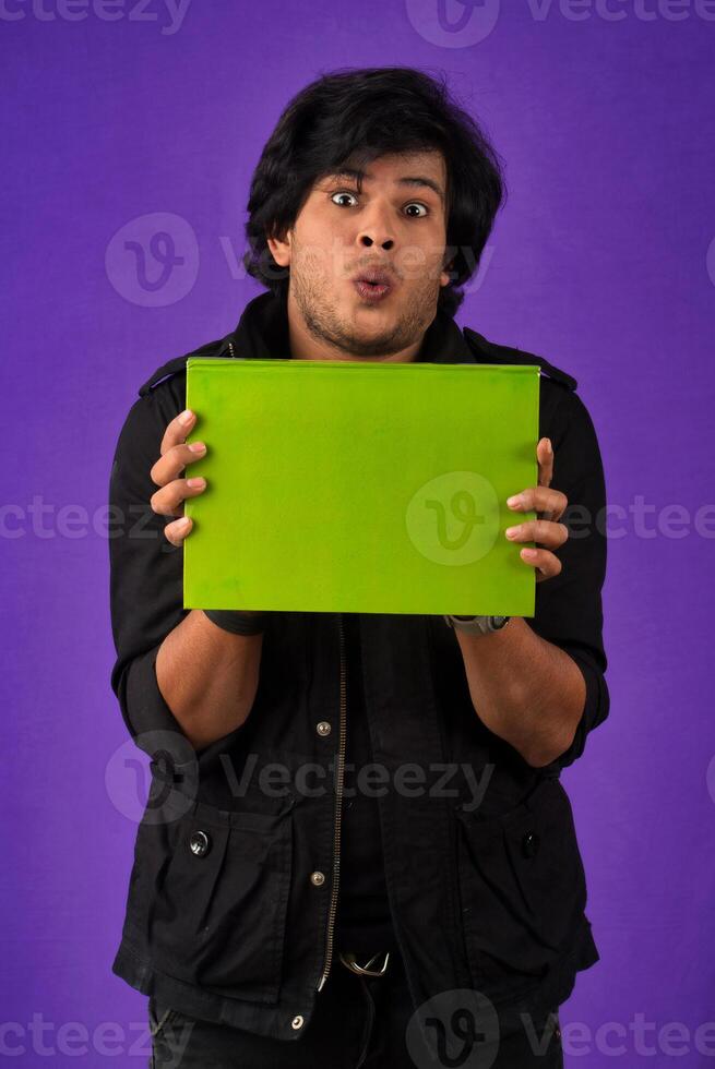 Young happy man holding and posing with the book on background. photo