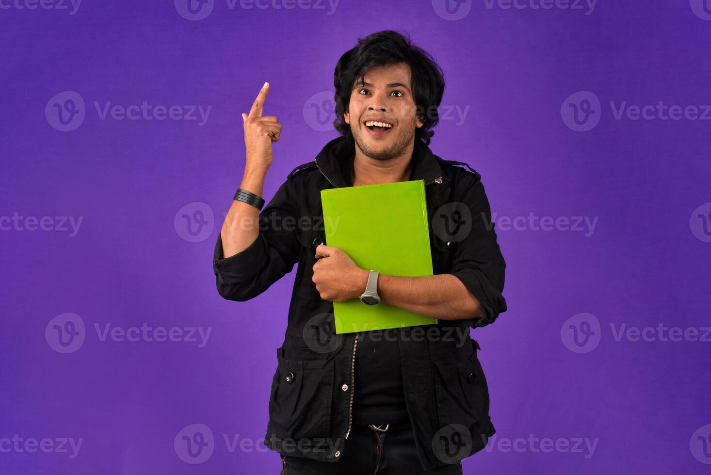 Young happy man holding and posing with the book on background. photo