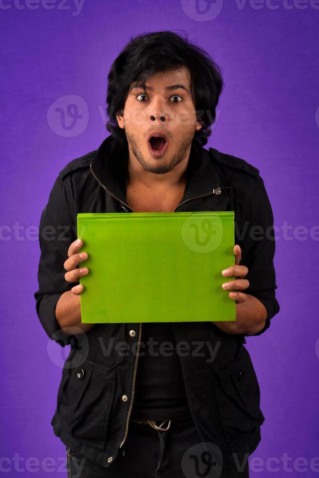 Young happy man holding and posing with the book on background. photo