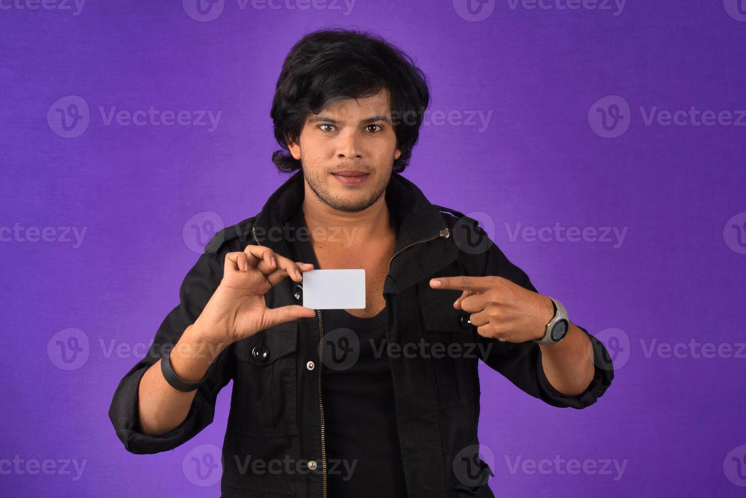 Young smiling handsome man posing with a credit card on purple background. photo