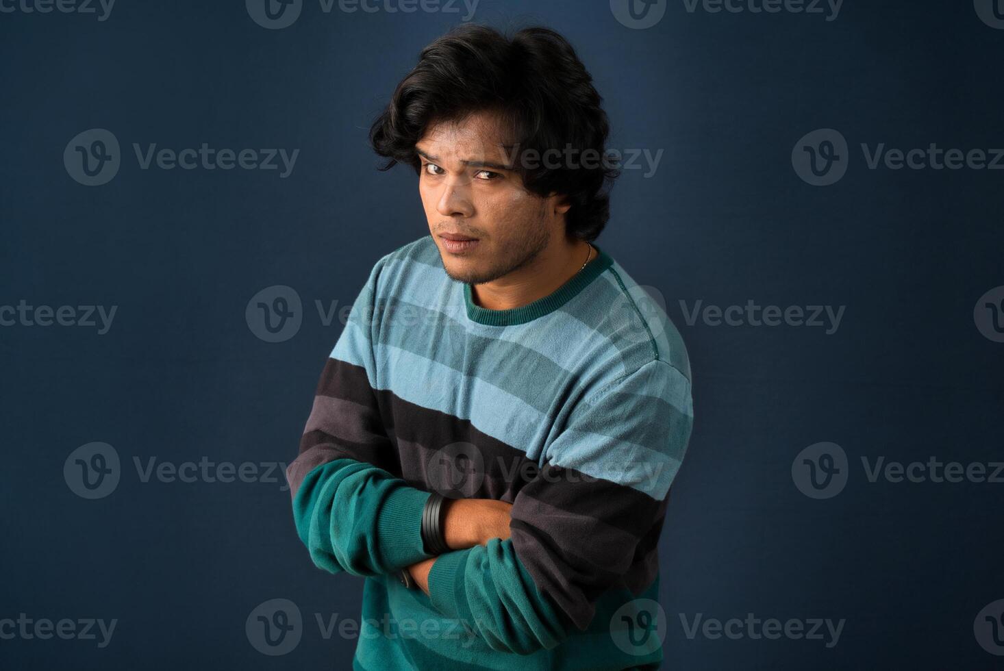 Portrait of Happy Indian young man with arms crossed against a dark background photo