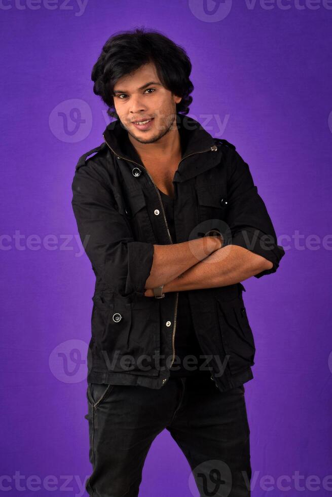 Portrait of Happy Indian young man with arms crossed against a dark background photo