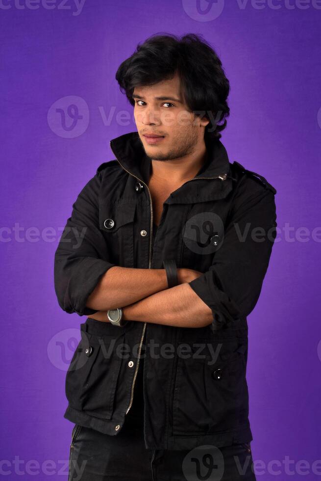 Portrait of Happy Indian young man with arms crossed against a dark background photo