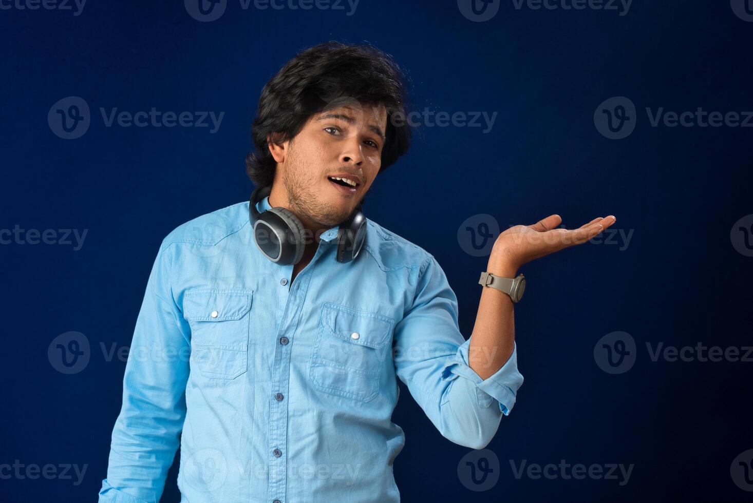 Portrait of a handsome young man enjoying music on headphones on blue background. photo