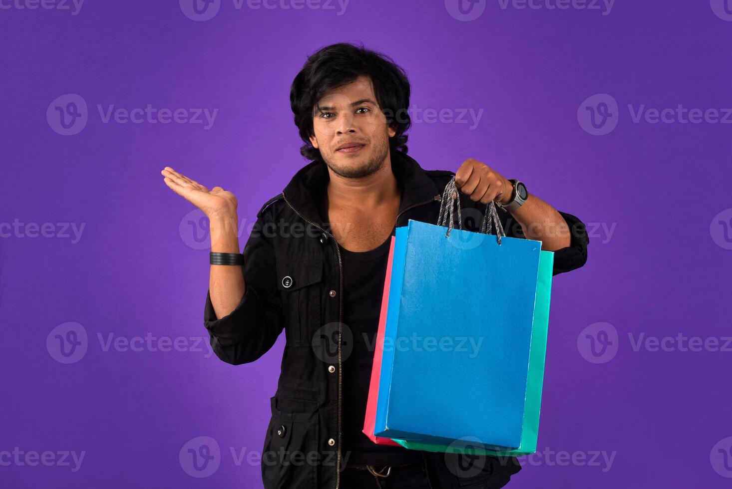 Beautiful Indian young handsome man holding and posing with shopping bags on a purple background photo