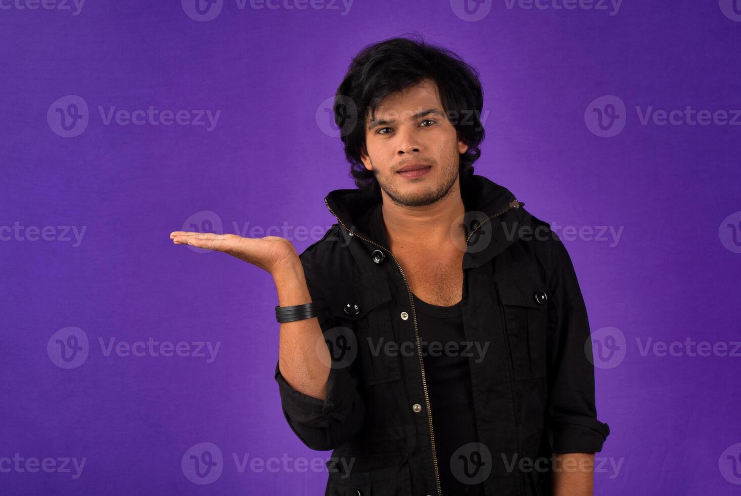 Portrait of a successful cheerful young man holding and presenting something on hand with a happy smiling face. photo