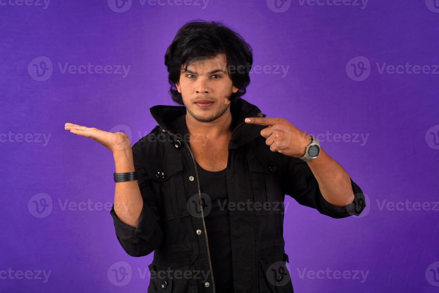 Portrait of a successful cheerful young man holding and presenting something on hand with a happy smiling face. photo