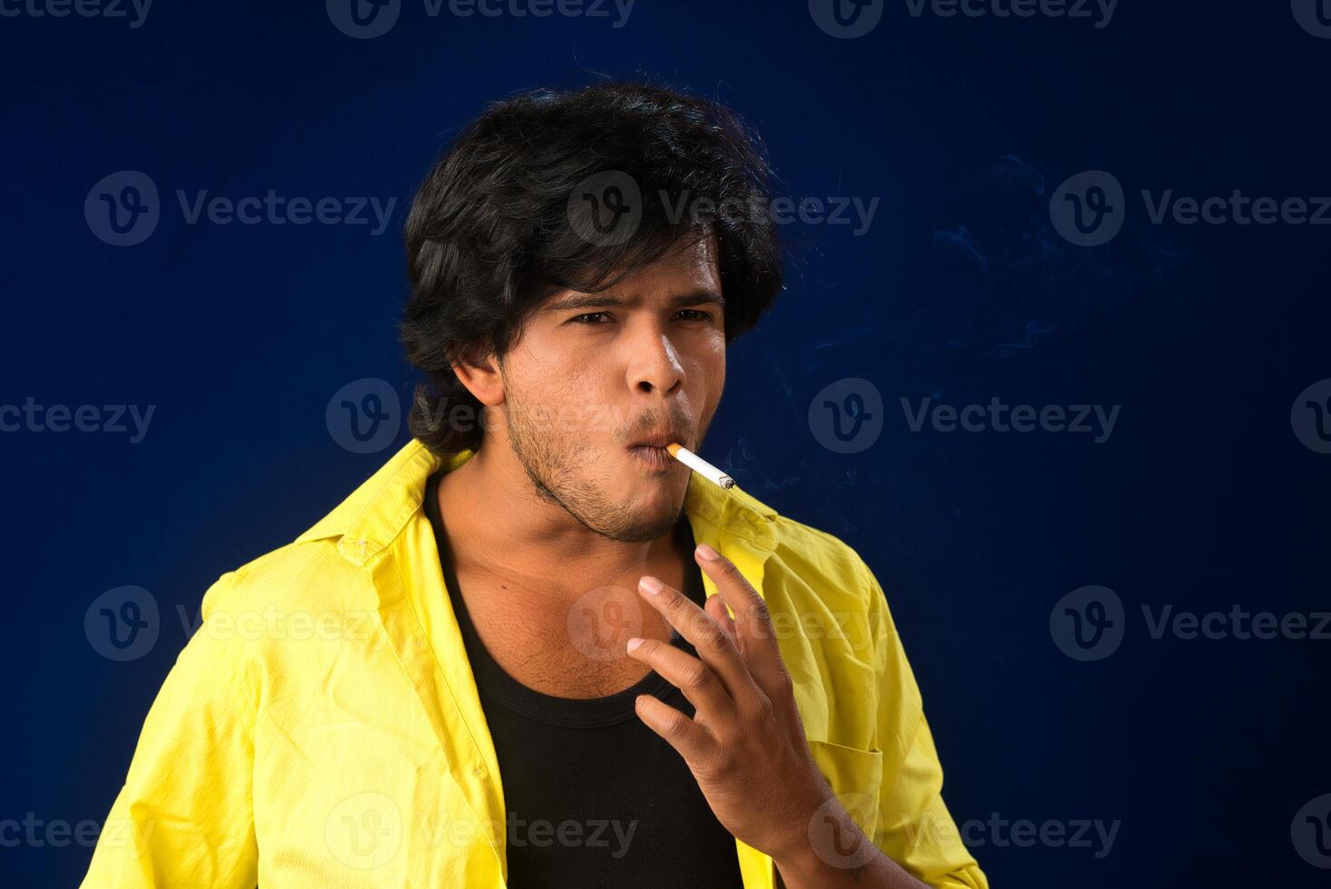 A young man smoking a cigarette and making a lot of smoke around. photo