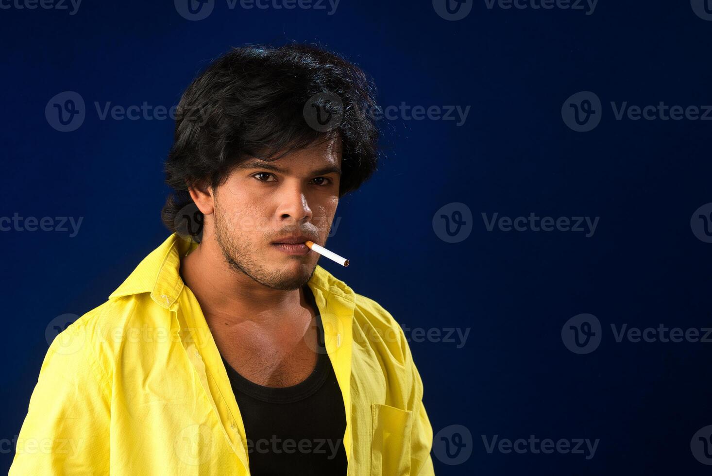 A young man smoking a cigarette and making a lot of smoke around. photo