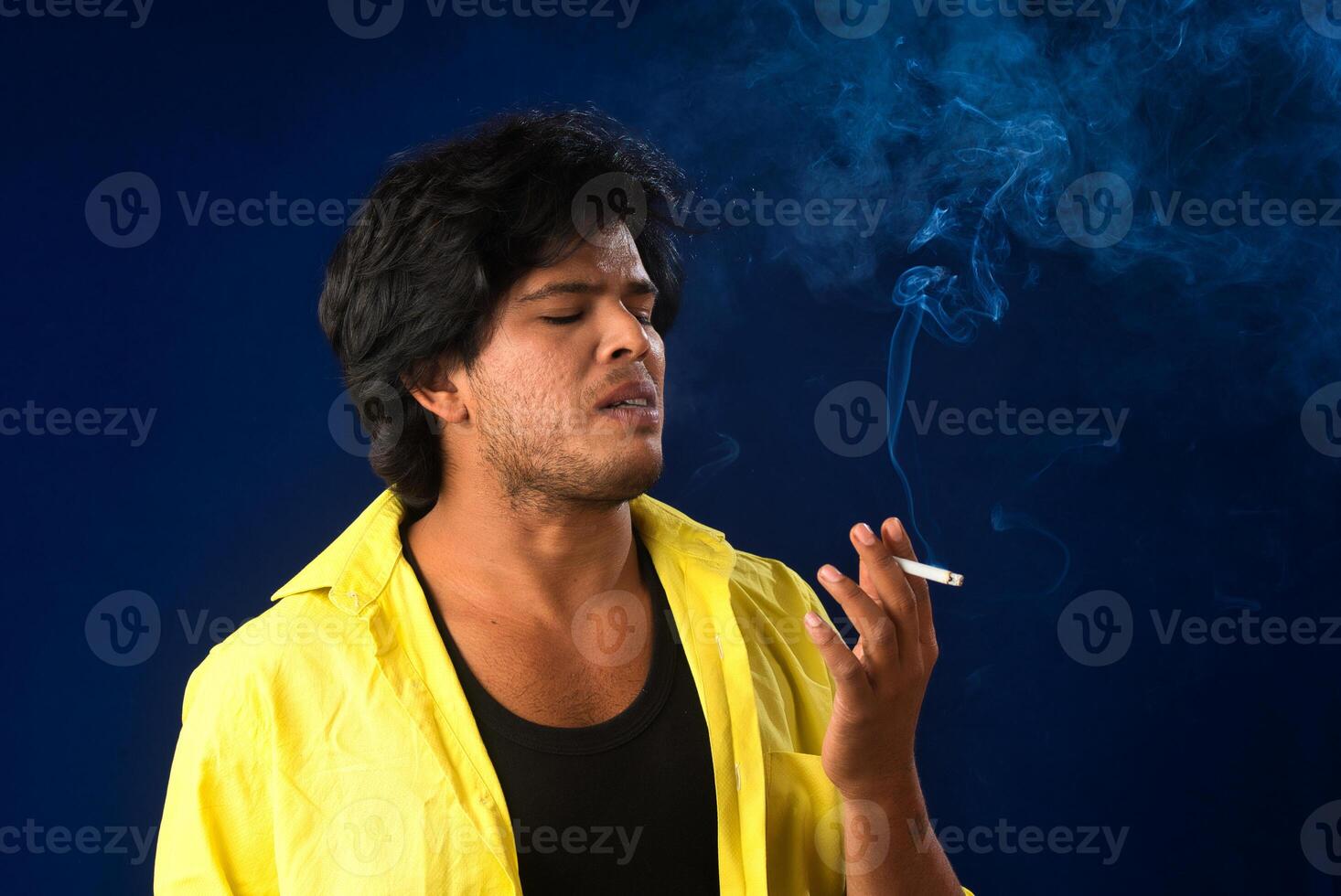 A young man smoking a cigarette and making a lot of smoke around. photo