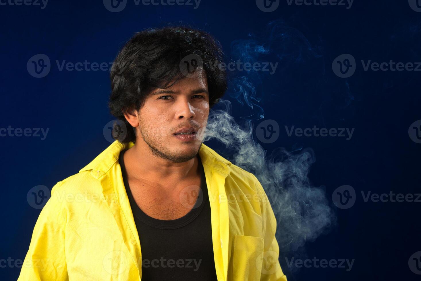 A young man smoking a cigarette and making a lot of smoke around. photo