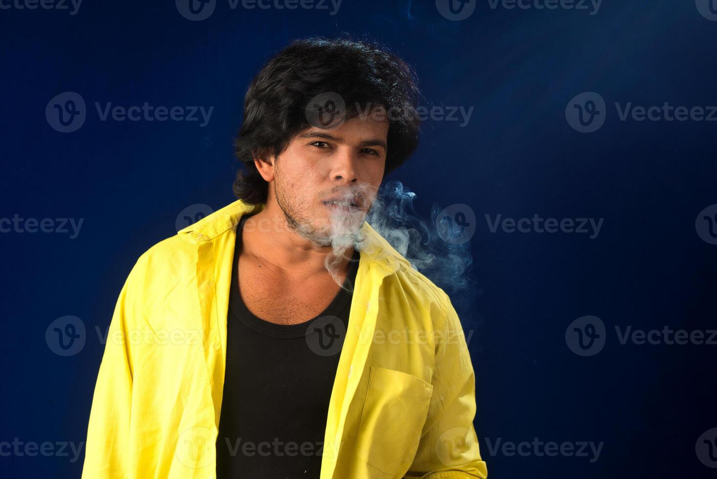 A young man smoking a cigarette and making a lot of smoke around. photo