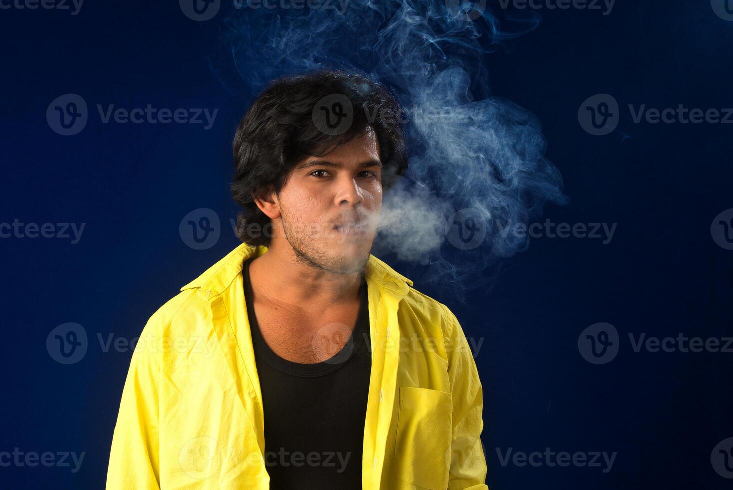 A young man smoking a cigarette and making a lot of smoke around. photo