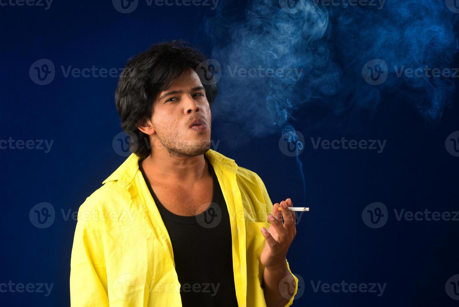 A young man smoking a cigarette and making a lot of smoke around. photo