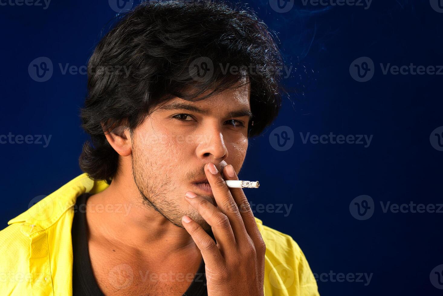A young man smoking a cigarette and making a lot of smoke around. photo