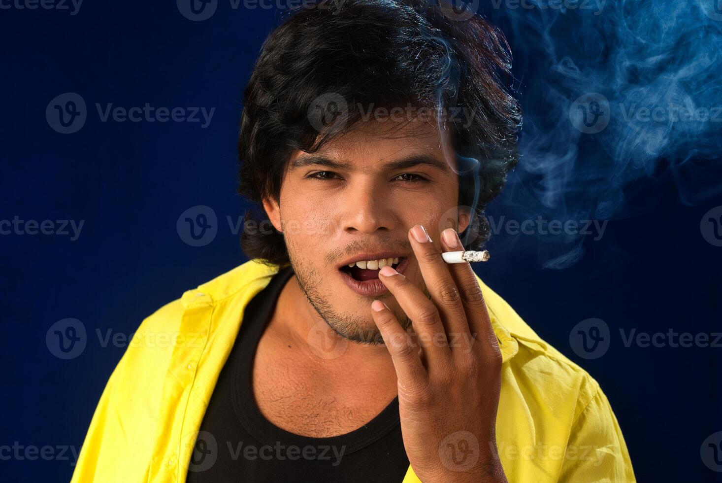 A young man smoking a cigarette and making a lot of smoke around. photo