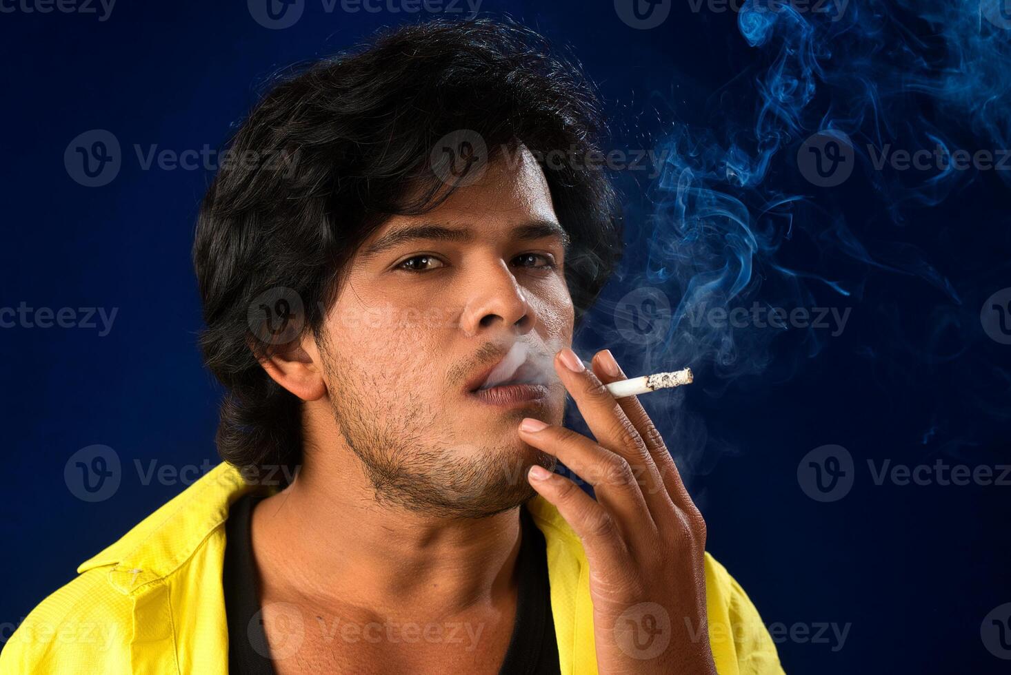 A young man smoking a cigarette and making a lot of smoke around. photo