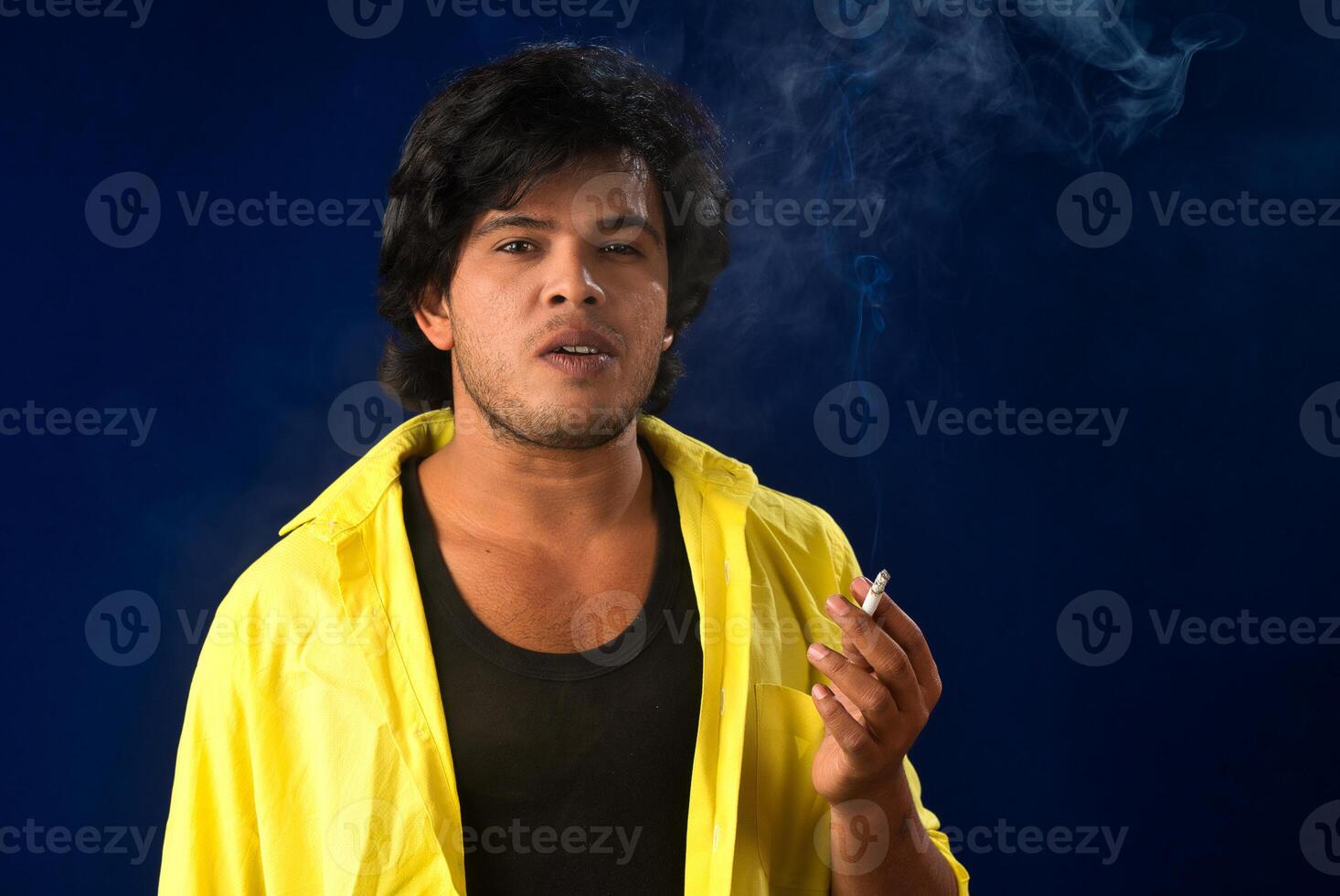 A young man smoking a cigarette and making a lot of smoke around. photo