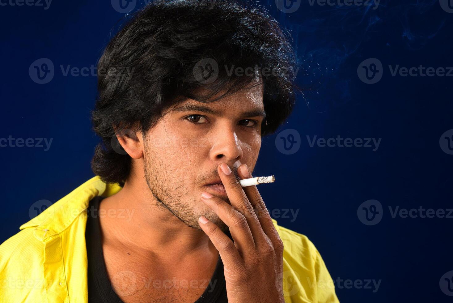 A young man smoking a cigarette and making a lot of smoke around. photo