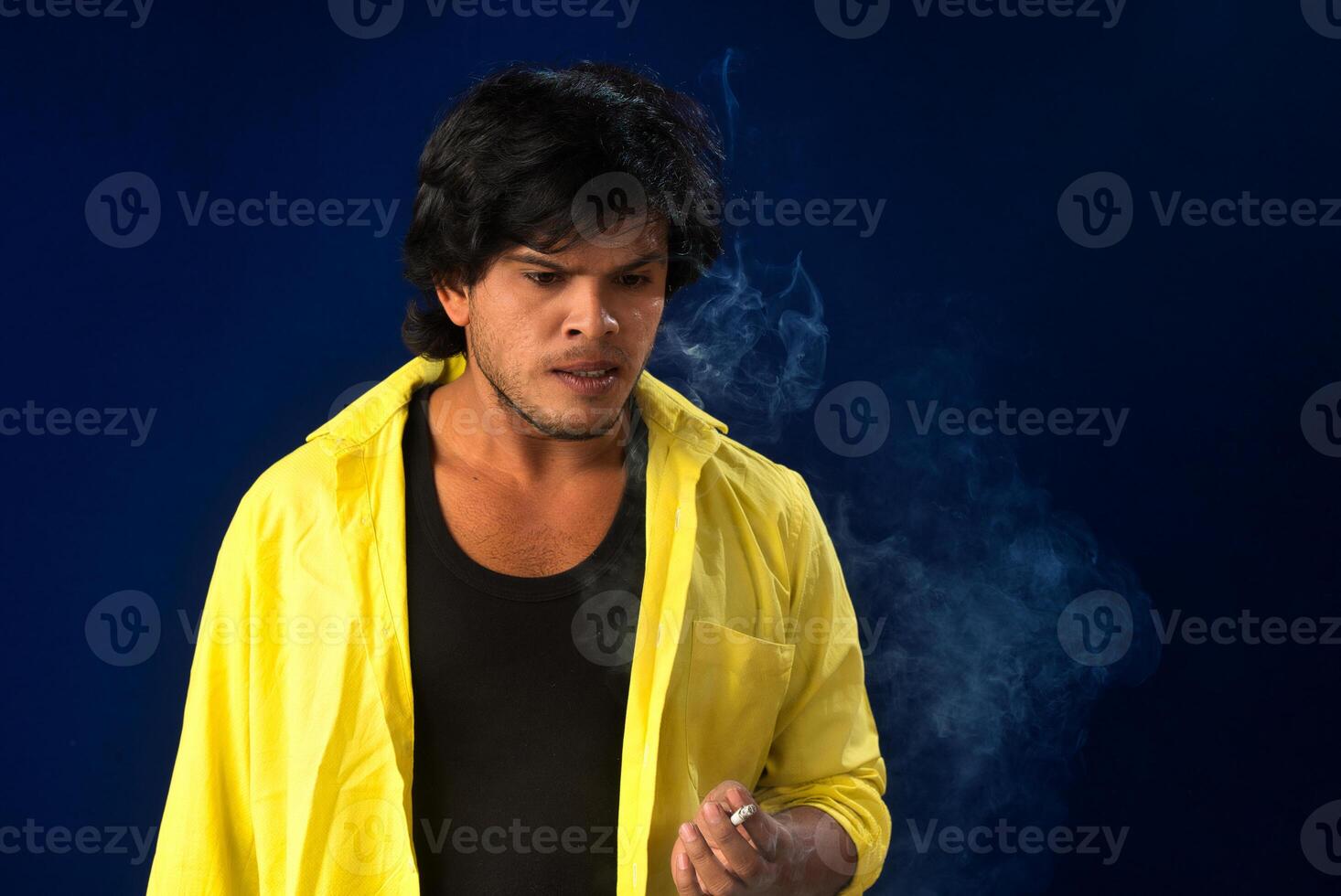 A young man smoking a cigarette and making a lot of smoke around. photo