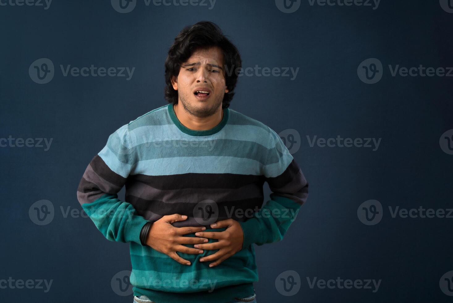 Unhappy man suffering from stomach ache over gray background. People, healthcare, and health problem concept. photo