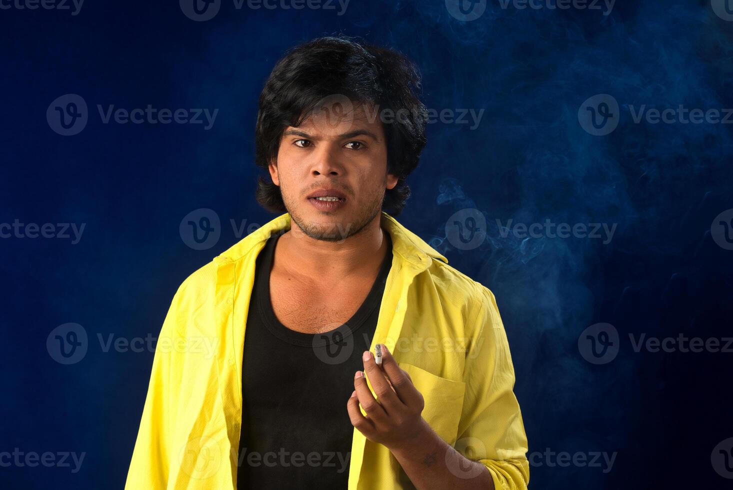 A young man smoking a cigarette and making a lot of smoke around. photo