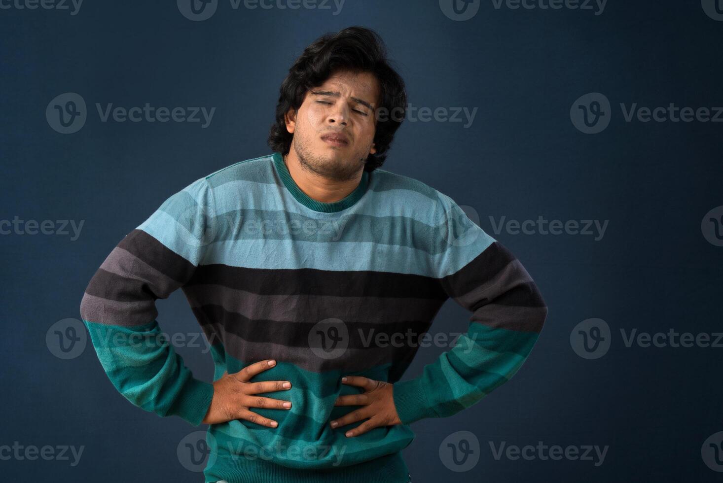 Unhappy man suffering from stomach ache over gray background. People, healthcare, and health problem concept. photo