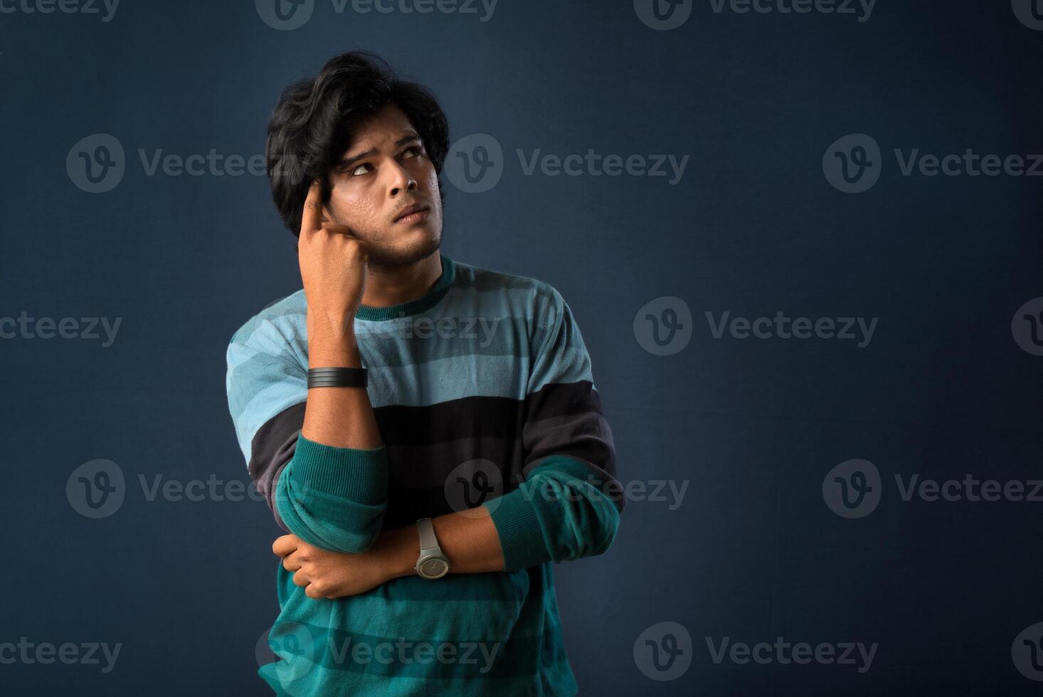 Portrait of a young man thinking on a dark background photo