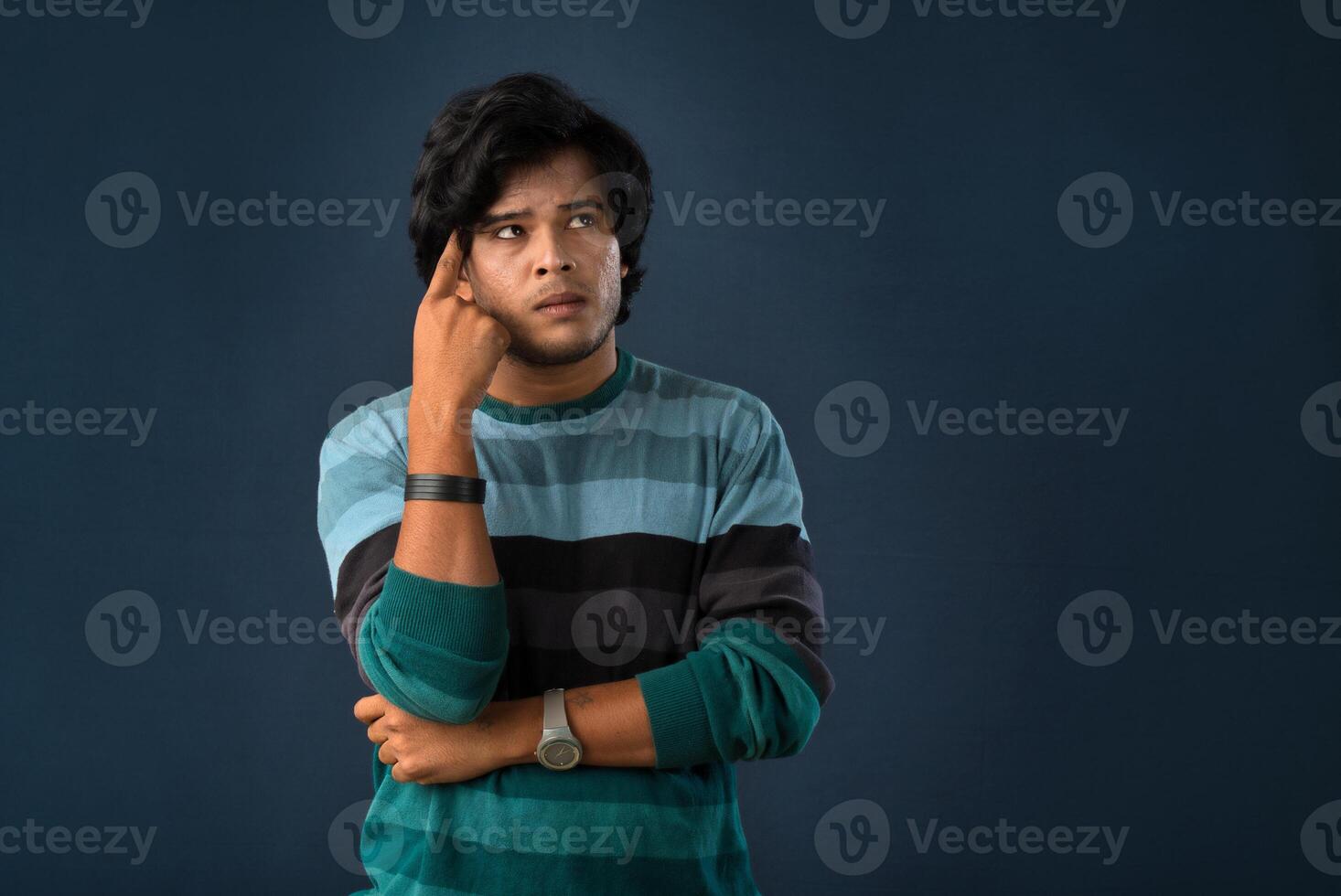 Portrait of a young man thinking on a dark background photo