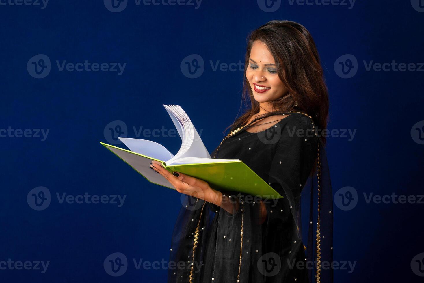 Pretty young girl posing with book on blue background photo