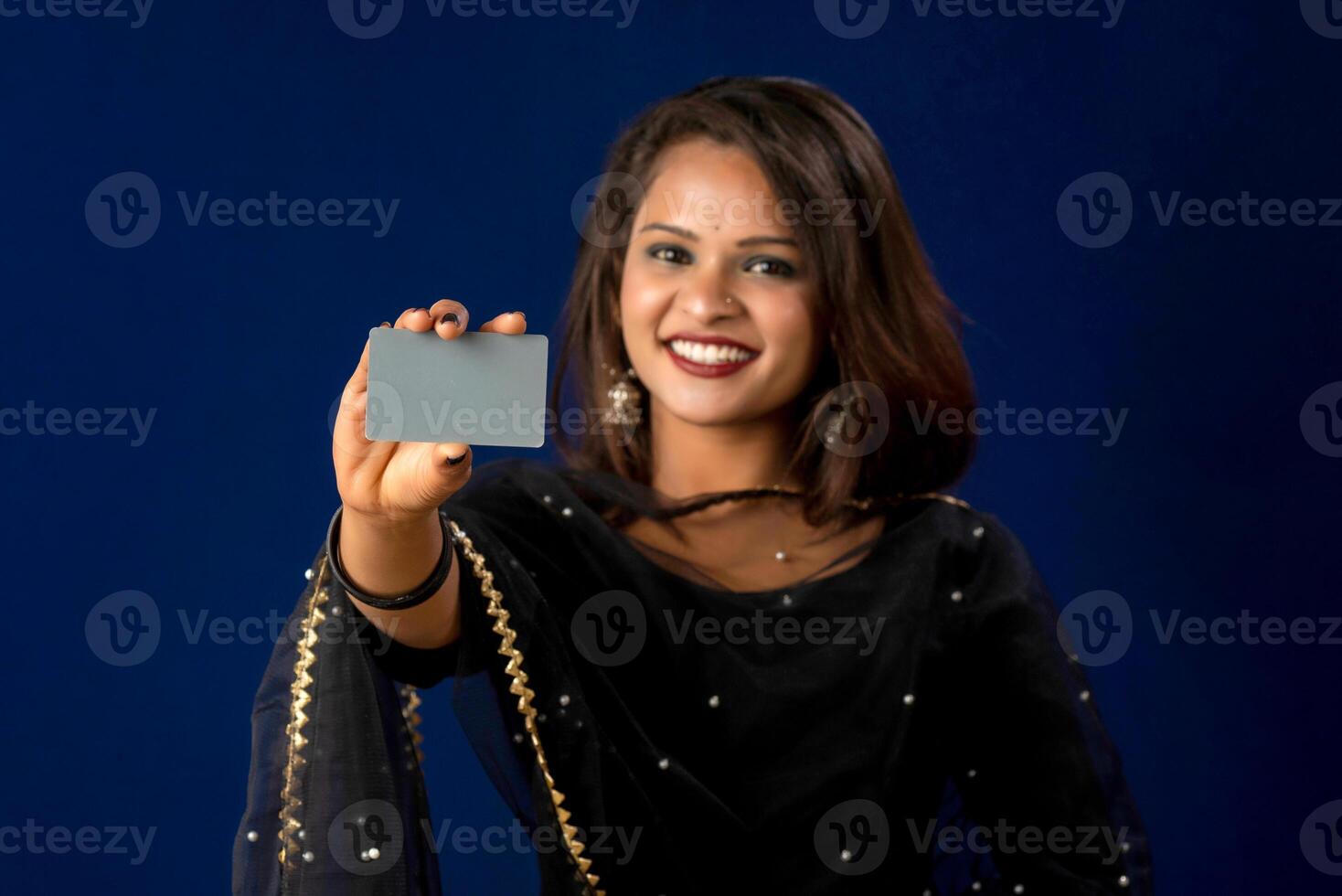 Young smiling beautiful girl posing with a credit or debit card on blue background. photo