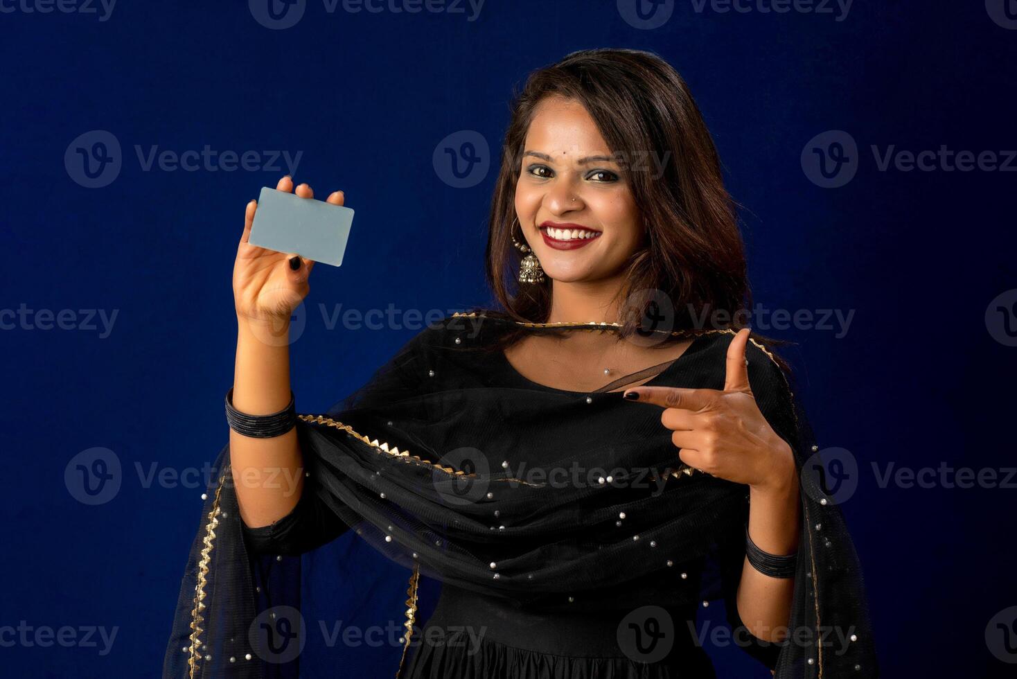 Young smiling beautiful girl posing with a credit or debit card on blue background. photo