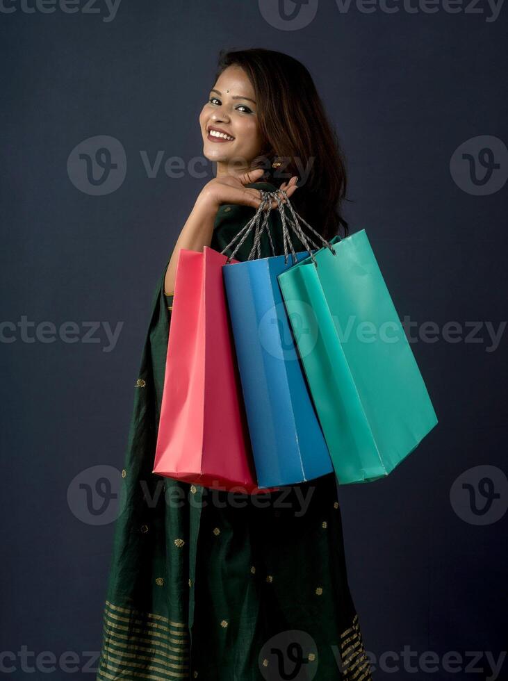 Beautiful Indian young girl or woman holding and posing with shopping bags on a dark background photo
