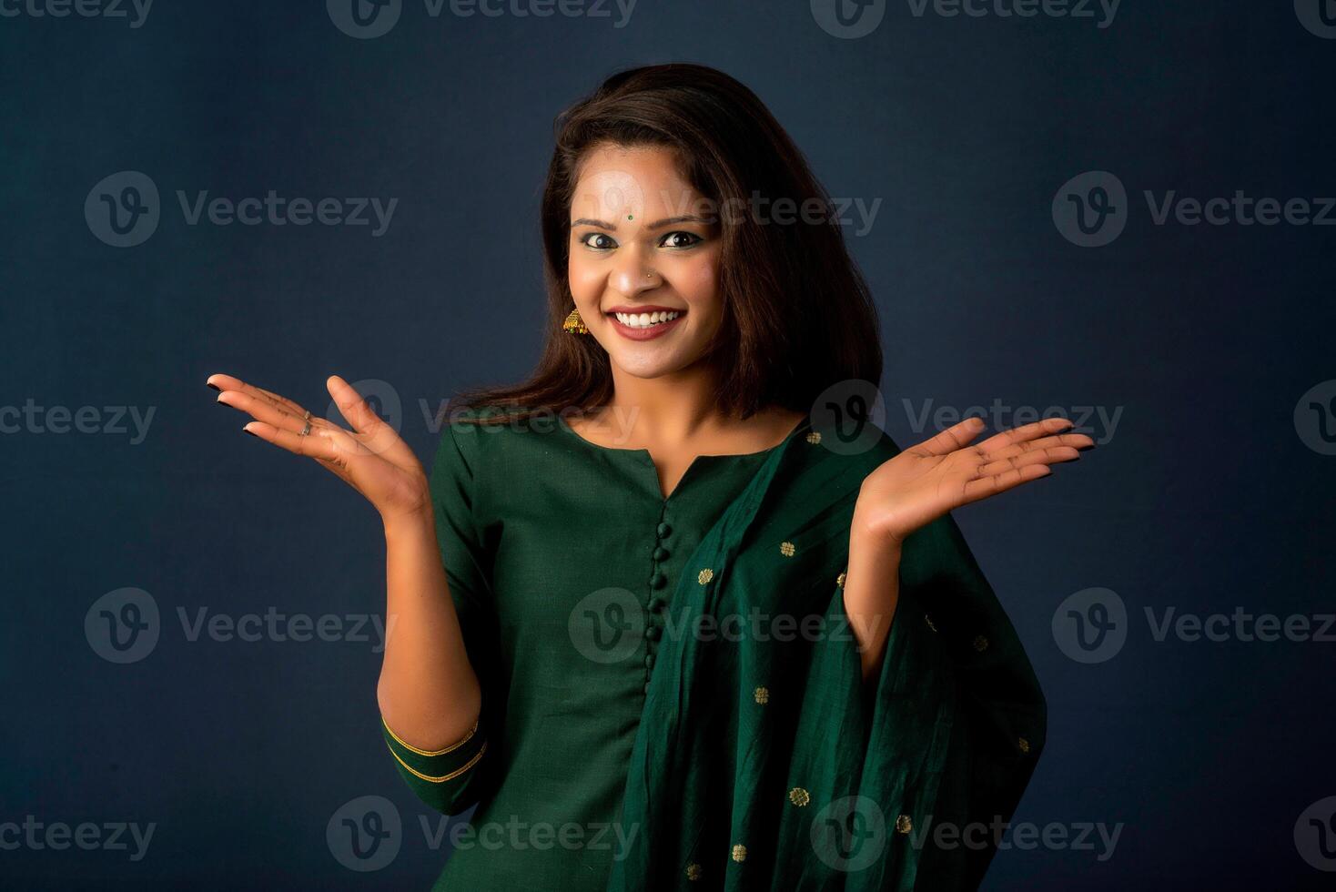 Portrait of a successful cheerful young girl presenting something with a fingers with a happy smiling face. photo