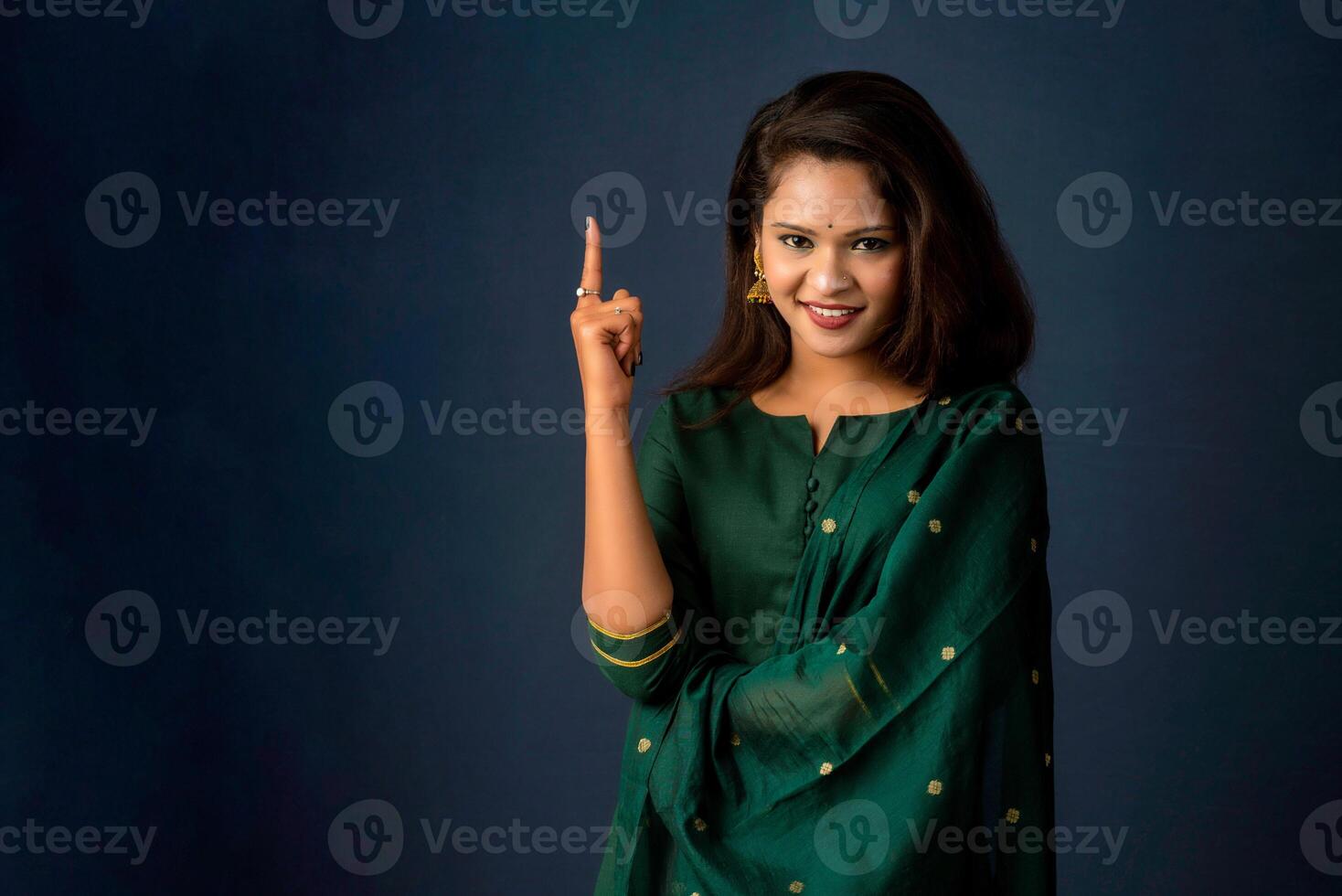 Portrait of a successful cheerful young girl presenting something with a fingers with a happy smiling face. photo
