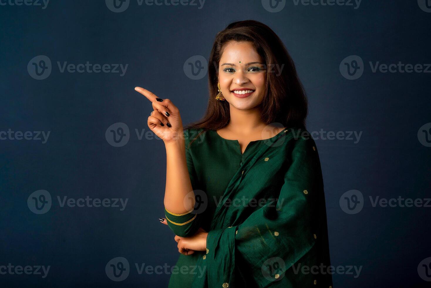 Portrait of a successful cheerful young girl presenting something with a fingers with a happy smiling face. photo