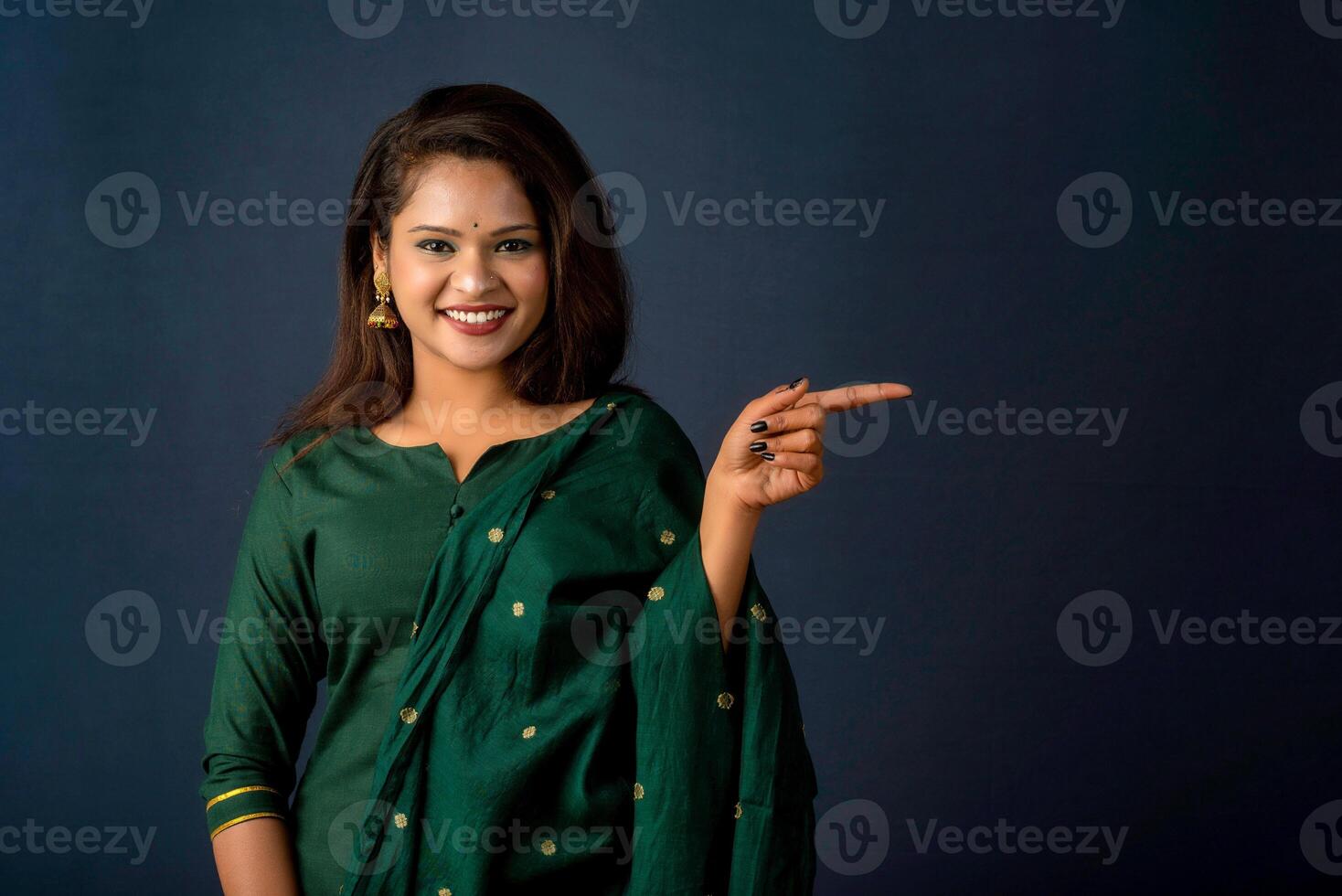 Portrait of a successful cheerful young girl presenting something with a fingers with a happy smiling face. photo