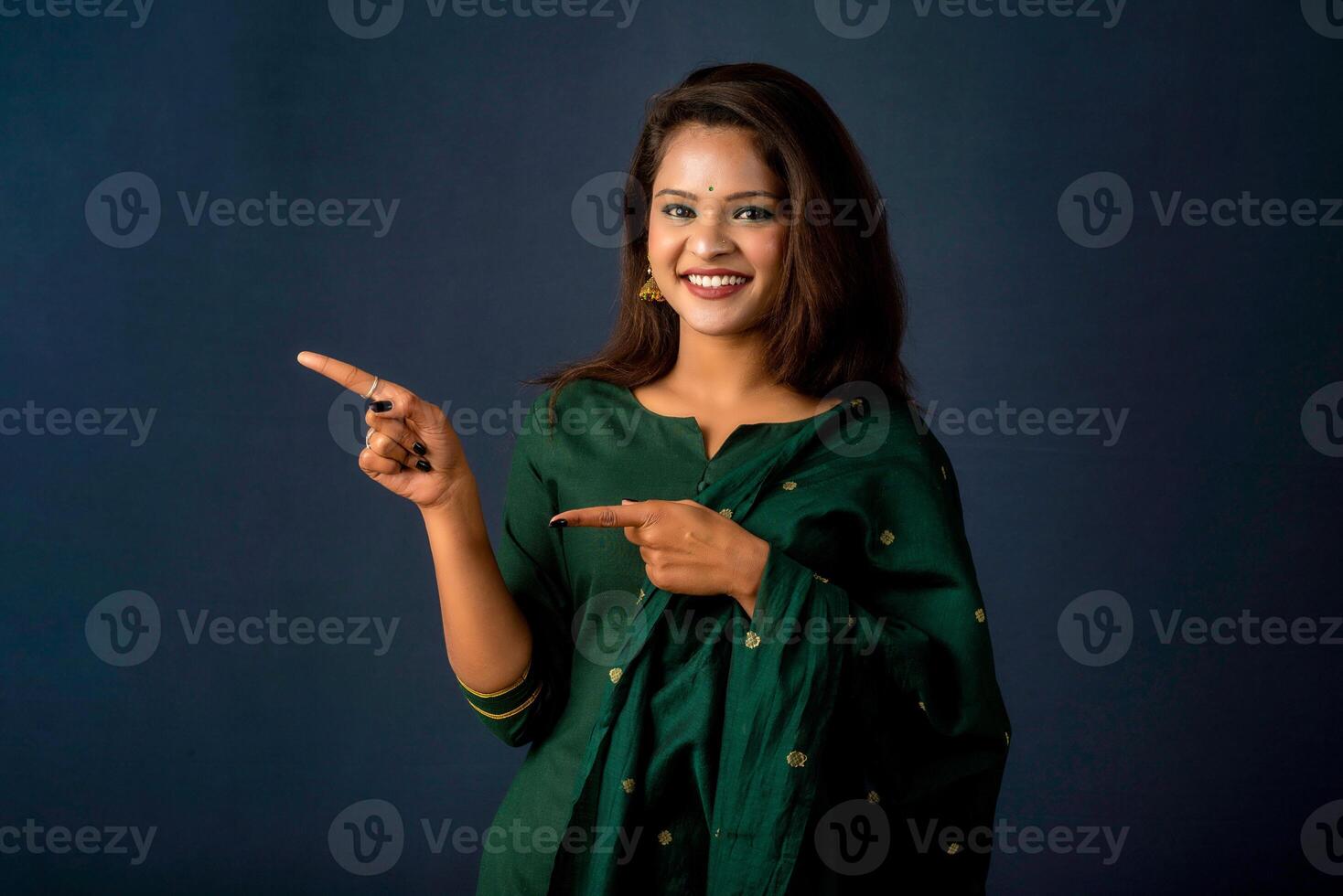 Portrait of a successful cheerful young girl presenting something with a fingers with a happy smiling face. photo