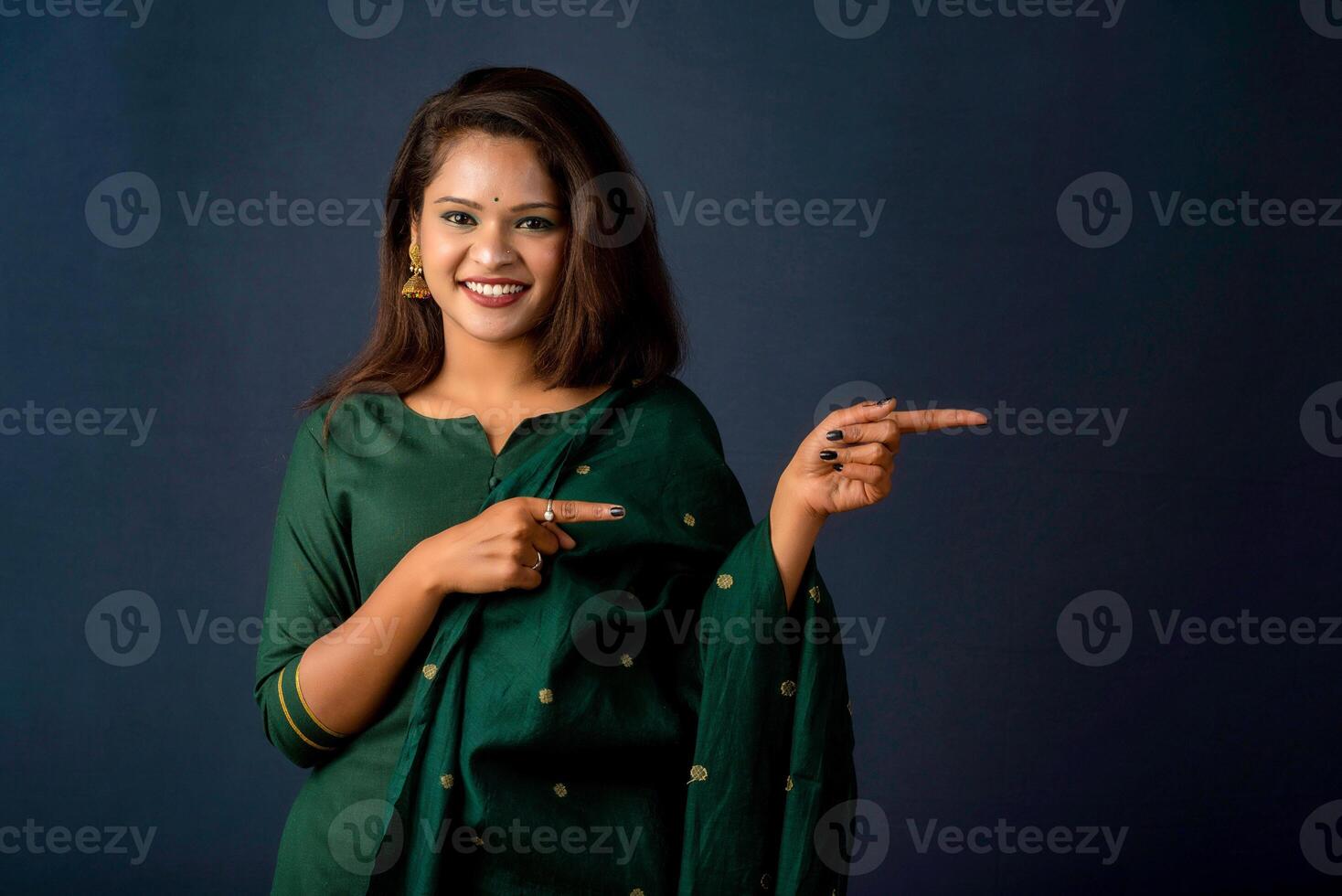Portrait of a successful cheerful young girl presenting something with a fingers with a happy smiling face. photo