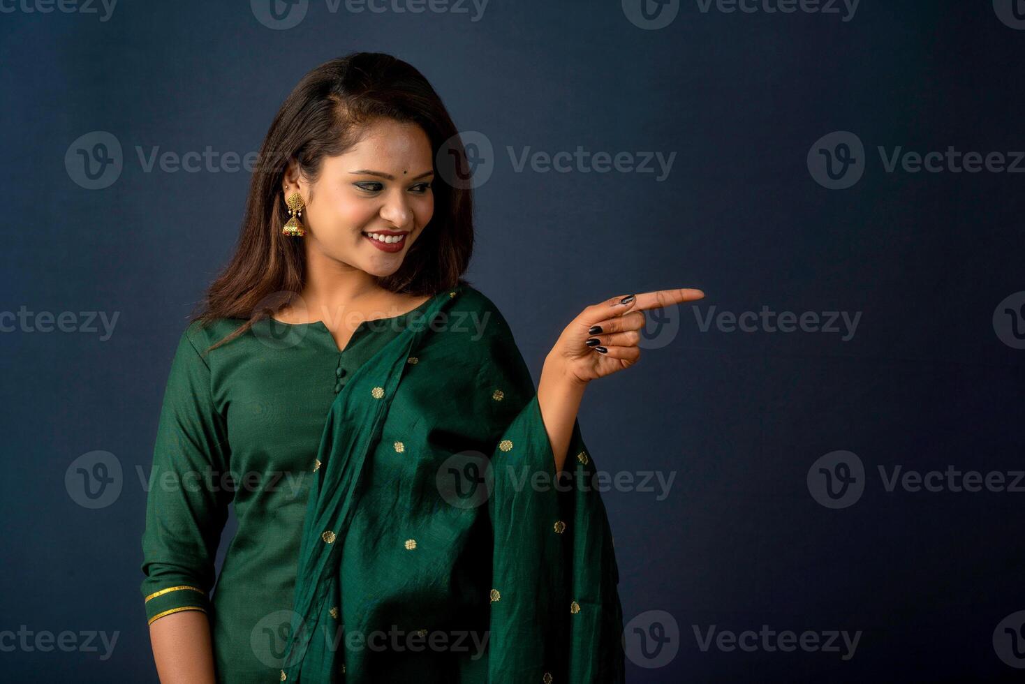 Portrait of a successful cheerful young girl presenting something with a fingers with a happy smiling face. photo