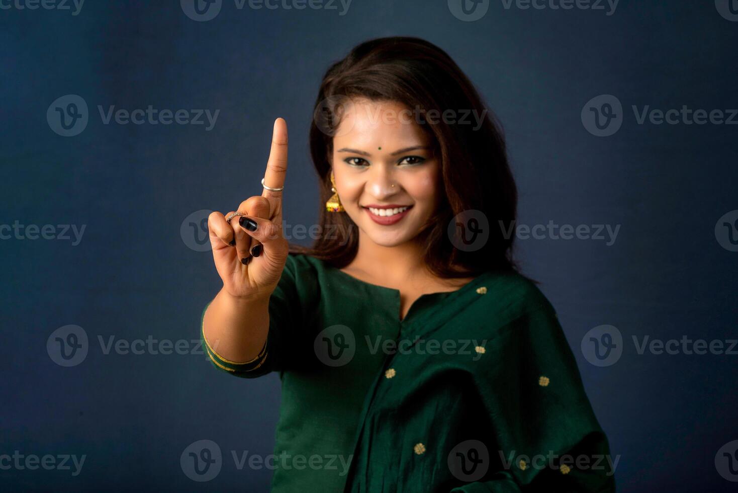 Portrait of a successful cheerful young girl presenting something with a fingers with a happy smiling face. photo