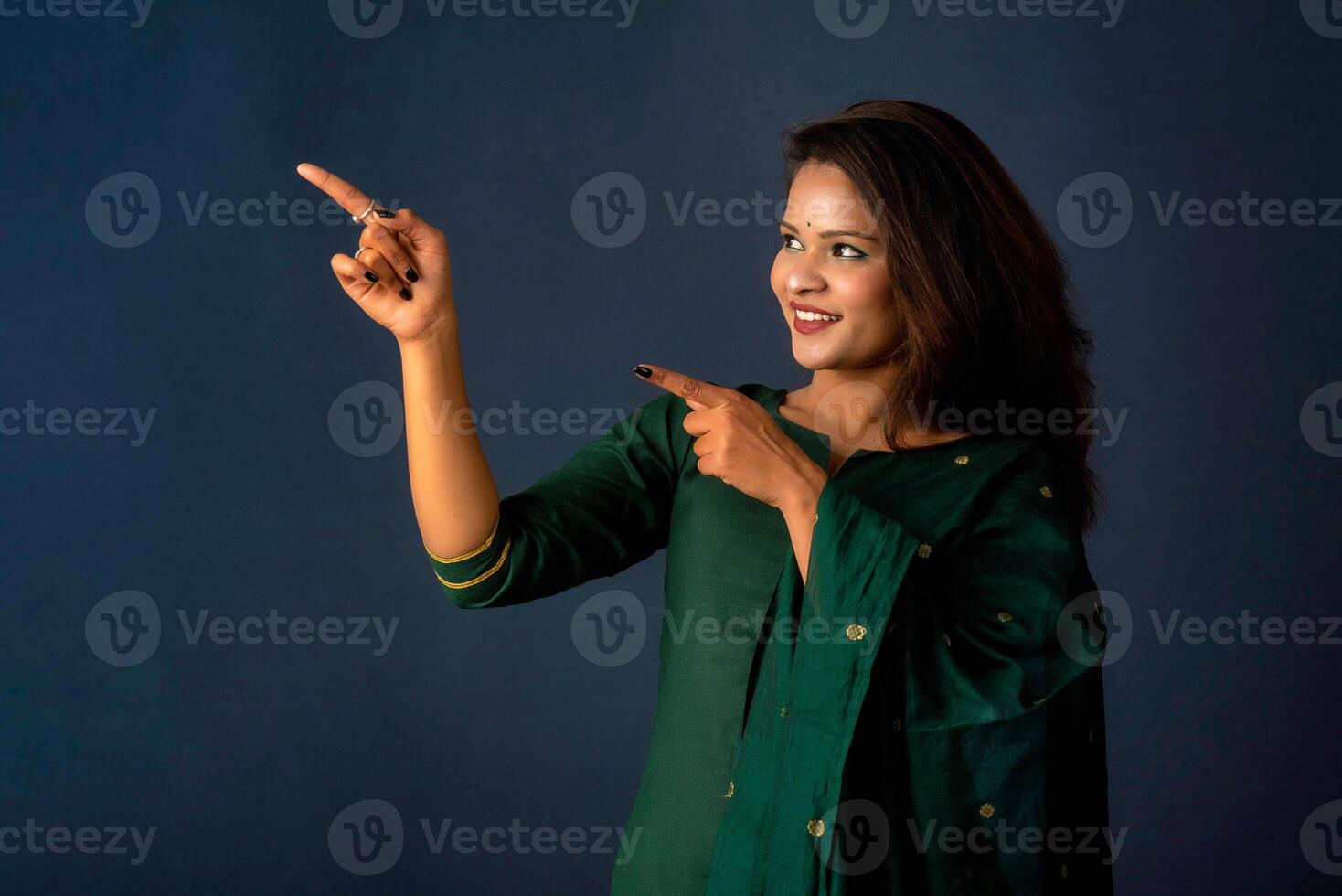 Portrait of a successful cheerful young girl presenting something with a fingers with a happy smiling face. photo