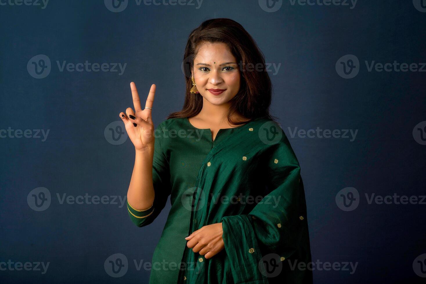 Young smiling girl showing ok sign or thumbs up on a grey background photo