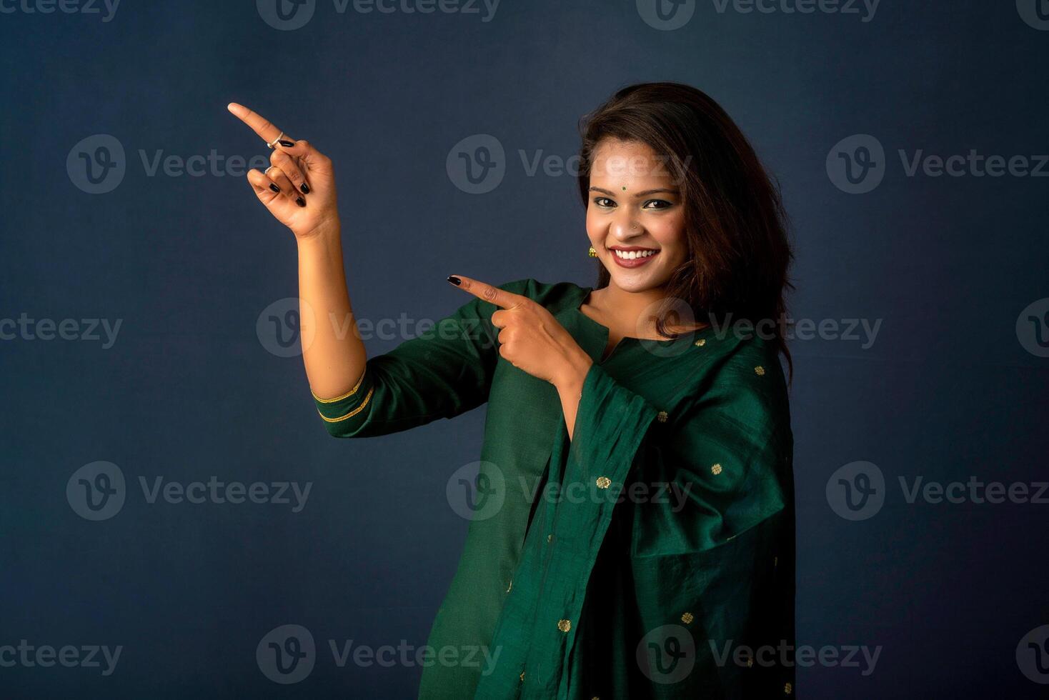 Portrait of a successful cheerful young girl presenting something with a fingers with a happy smiling face. photo